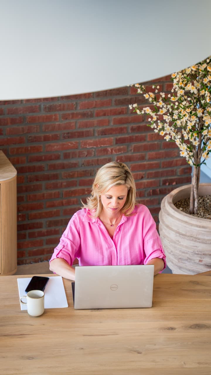 Nele Seys werkt aan haar laptop aan een houten tafel